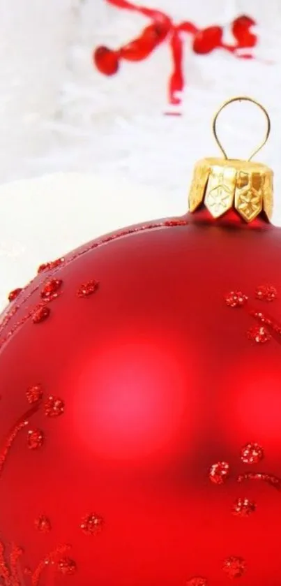 Red Christmas ornament on snowy backdrop.