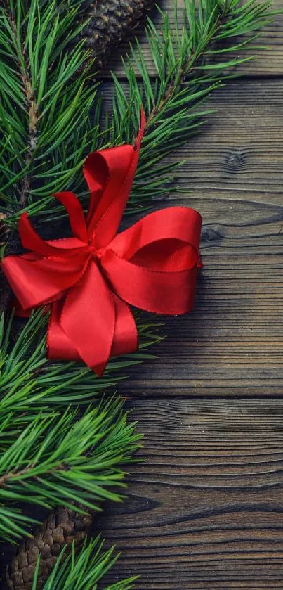 Red ribbon on pine branches with wooden background, ideal for festive wallpaper.