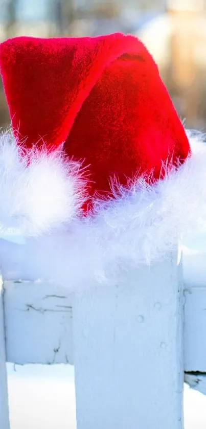 Red Santa hat resting on a snowy white fence