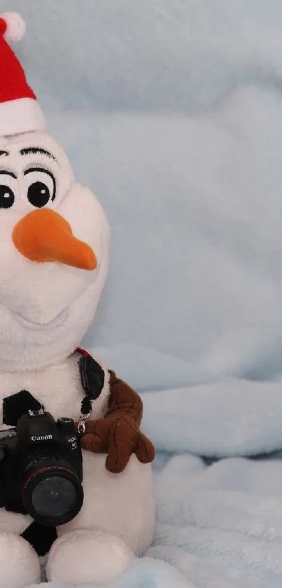 Cute snowman plush with Santa hat and camera on light blue background.