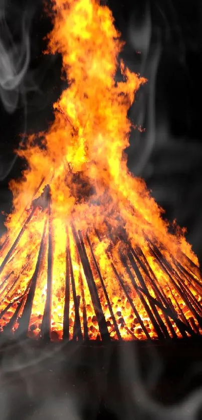 Bonfire with intense flames and smoke at night.