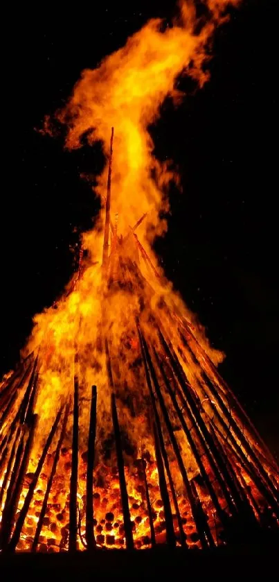 Vibrant bonfire at night with towering flames and dark backdrop.