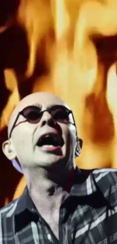 Musician with sunglasses on stage, fiery background.