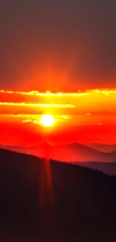 Vibrant sunset over rolling hills with orange sky.