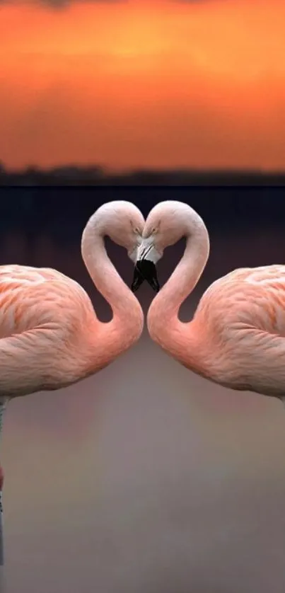 Two flamingos form a heart against a vibrant sunset.