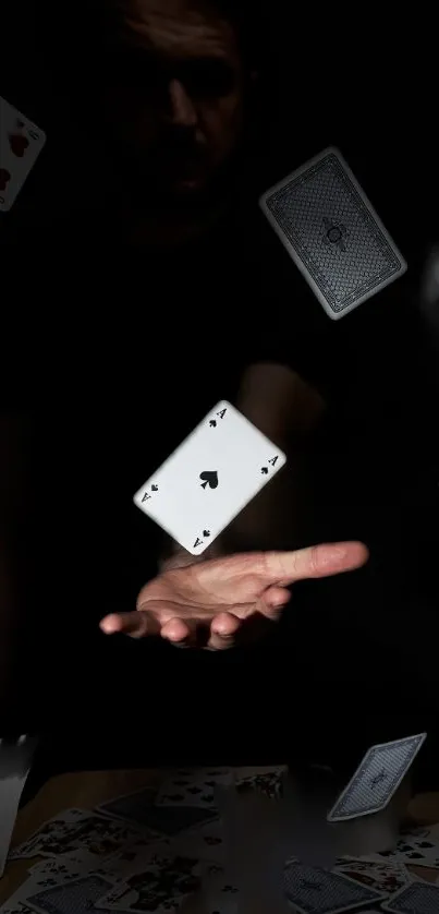 A hand levitates playing cards against a dark background.