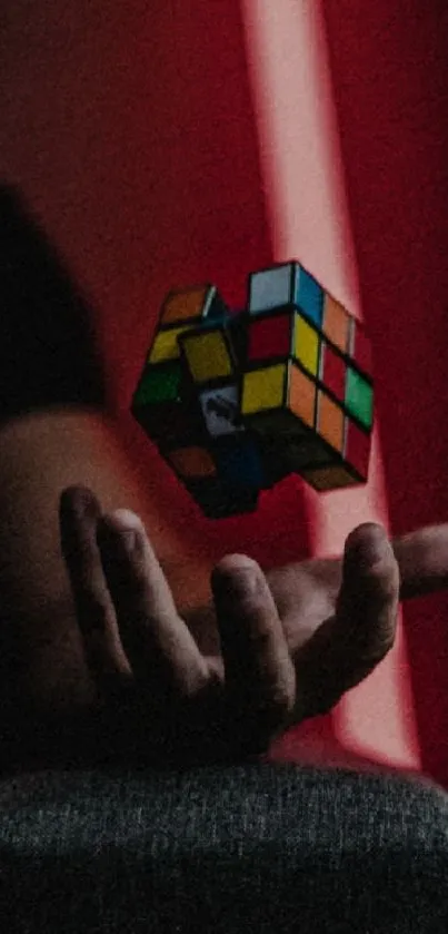 Floating Rubik's Cube with hand in red background.