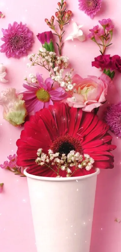 A vibrant bouquet of flowers in a cup on pink background.