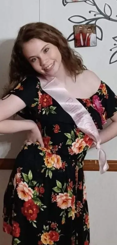 Woman in a black floral dress posing elegantly indoors.