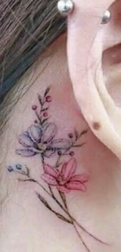 Delicate floral tattoo on ear with pink and purple hues.