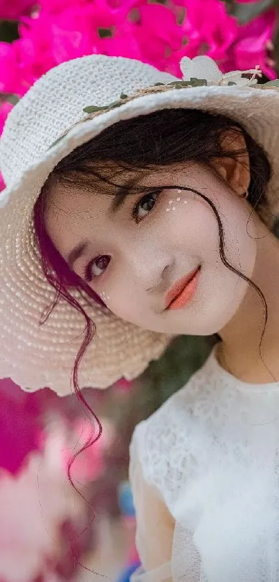 Woman with white hat surrounded by vivid pink flowers.