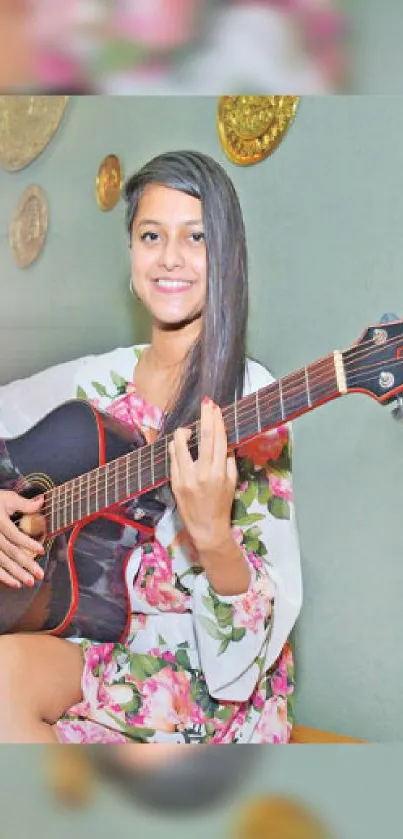 Young woman with guitar, floral dress, on stylish wallpaper.