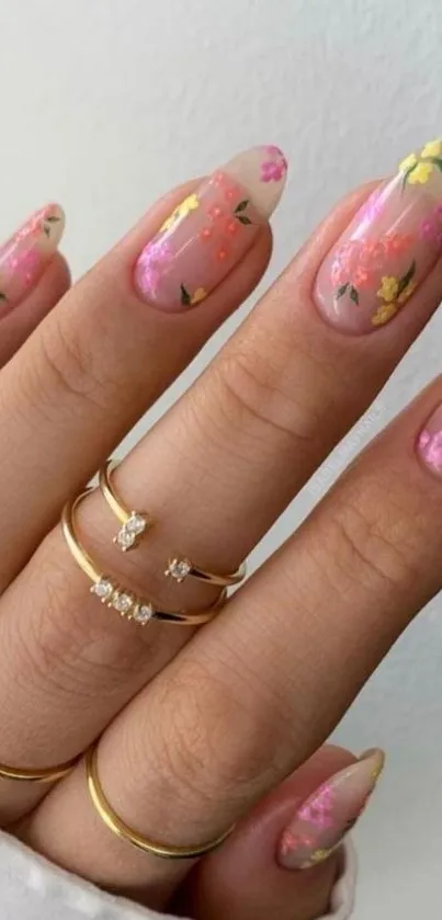 Hand with floral nails and gold rings on fingers.