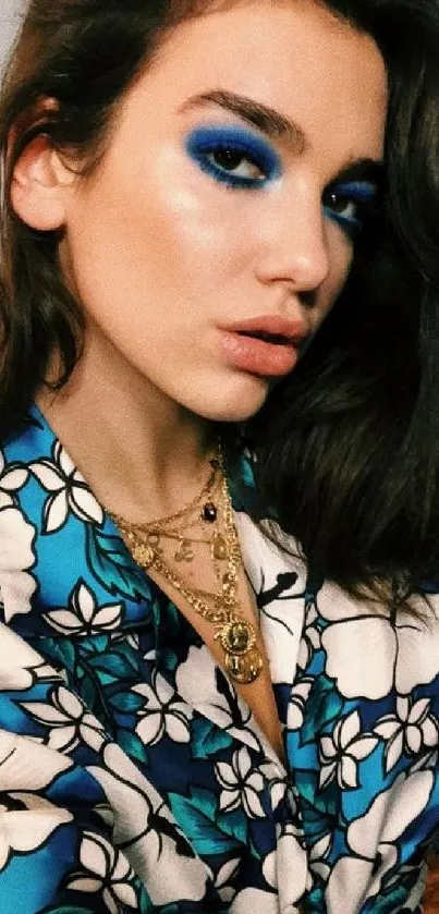 Portrait of woman with blue floral shirt and bold blue eye makeup.