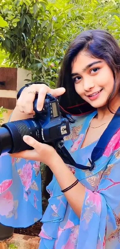 Woman in floral attire holding a camera.