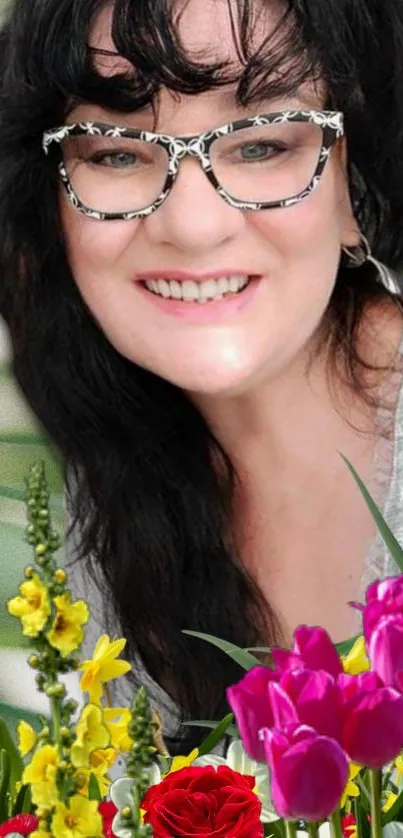 Smiling woman with glasses among colorful flowers.