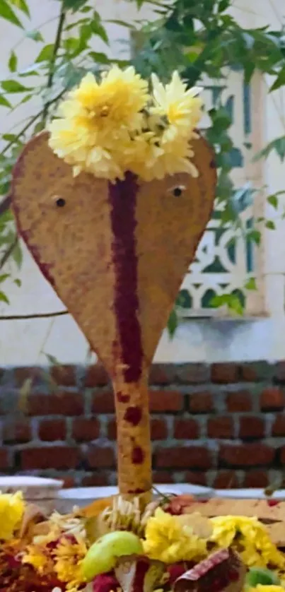 Snake deity with yellow flower garland against a natural backdrop.