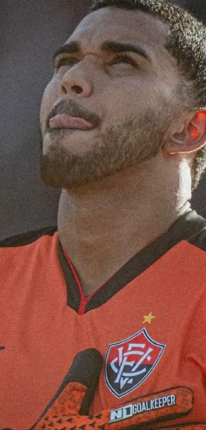 Portrait of a football player in an orange jersey, looking focused.
