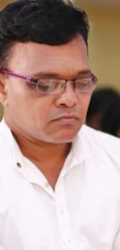 Man wearing glasses in a white shirt, looking focused.