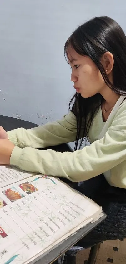 Young woman focused on phone during study session.