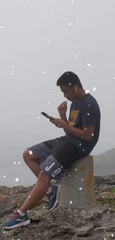 Lone figure in introspection on foggy seaside with gentle snowfall.