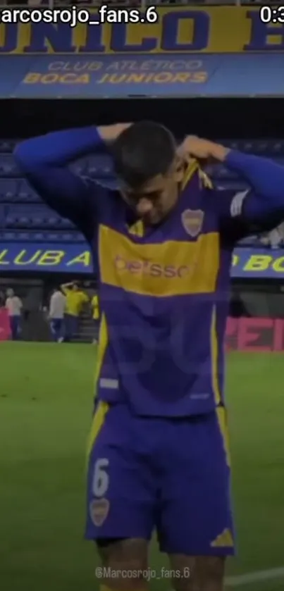 Football player in Boca Juniors jersey at stadium.