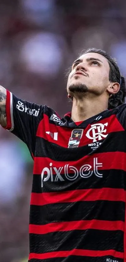 Football player in victory pose wearing red and black jersey.