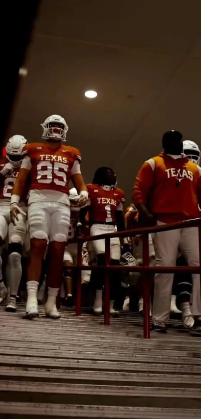 Football players in orange jerseys walking through a tunnel.