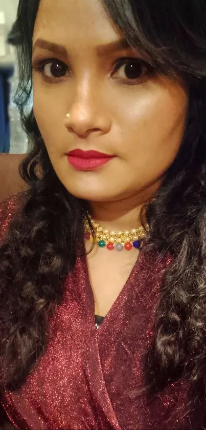 Woman in a burgundy outfit with intricate braids and vibrant jewelry.