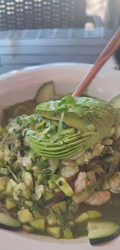 A vibrant salad with avocado and shrimp in a green setting.