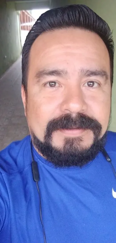 A man in a blue athletic shirt in a hallway.