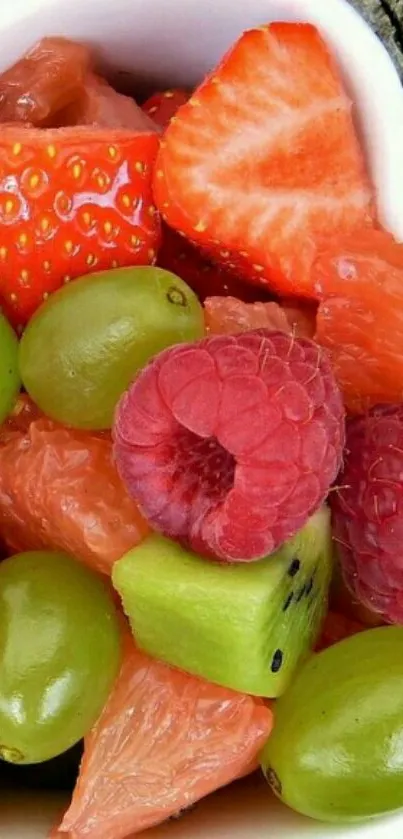 Heart-shaped bowl filled with colorful fruits, including strawberries and grapes.