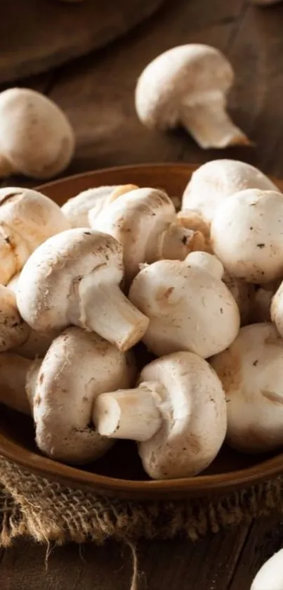 A bowl of fresh white mushrooms on a rustic wooden surface.