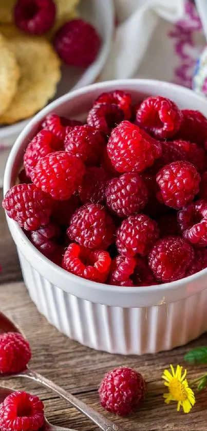 A white bowl filled with fresh red raspberries on a wooden table.