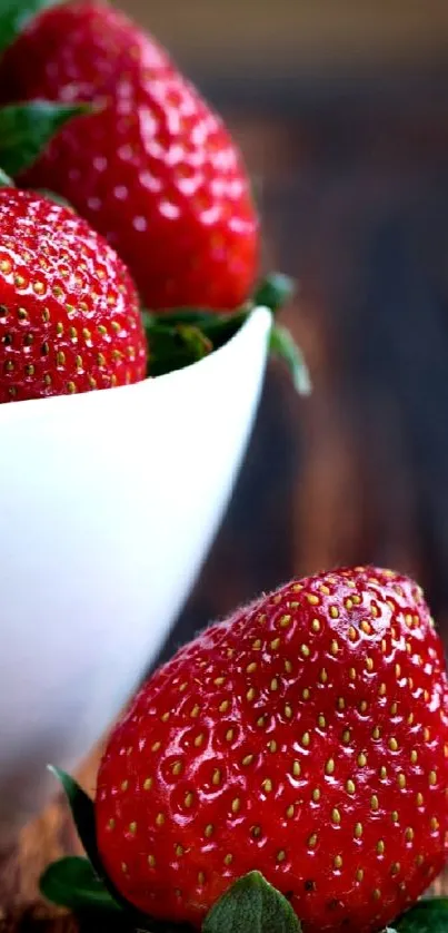 Fresh red strawberries in white bowl on wooden table wallpaper.