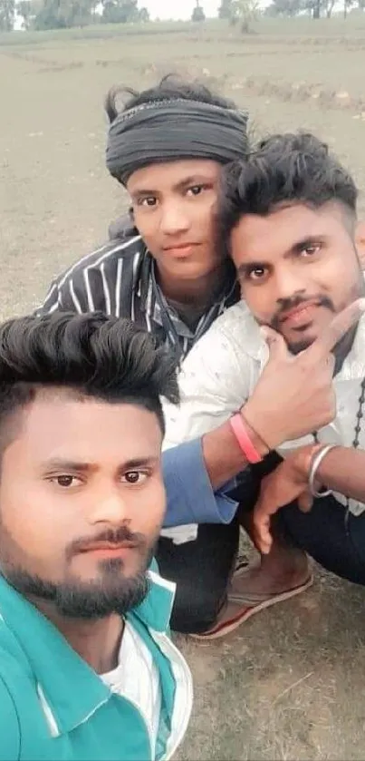 Three friends posing in a grassy field, smiling at the camera.