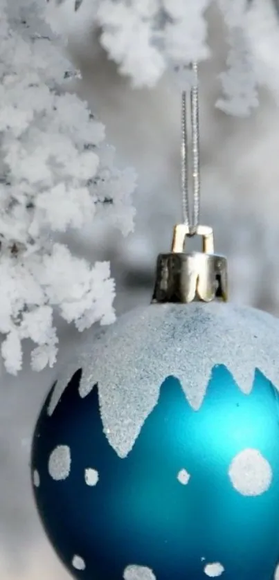 Frosty blue Christmas ornament hanging on snowy branches.