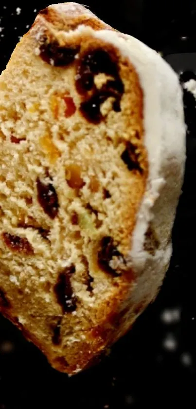 Slice of fruit cake on black background with sugar icing.