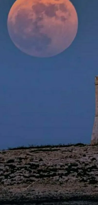 Full moon rising over a coastal tower against a deep blue night sky.