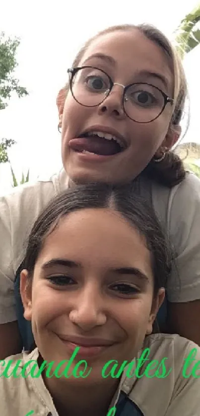 Two girls having fun outdoors with green background.