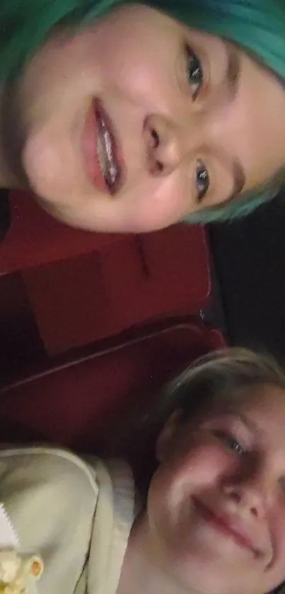 Friends taking a selfie in theater seats, with vibrant colors and popcorn.