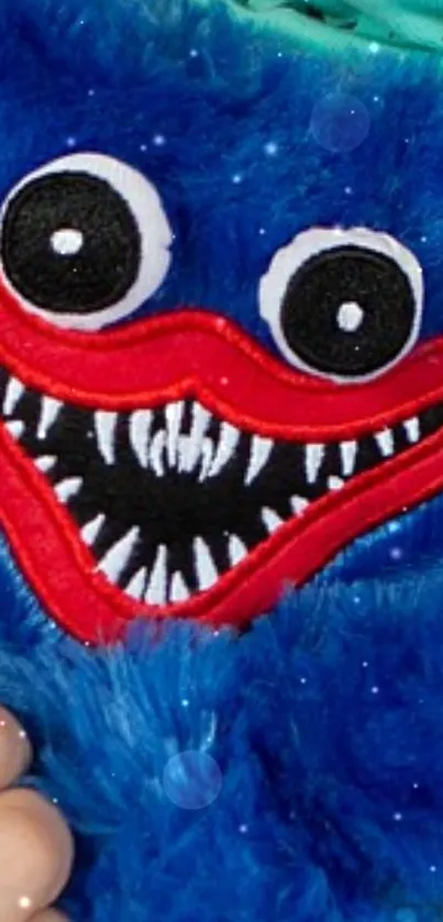 Blue furry creature with playful smile on mobile wallpaper.