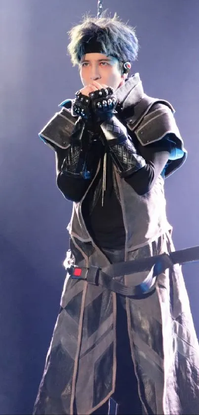 Futuristic performer in dark costume with blue lighting on stage.