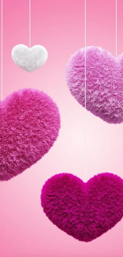 Pink fuzzy hearts hanging on a light pastel pink background.