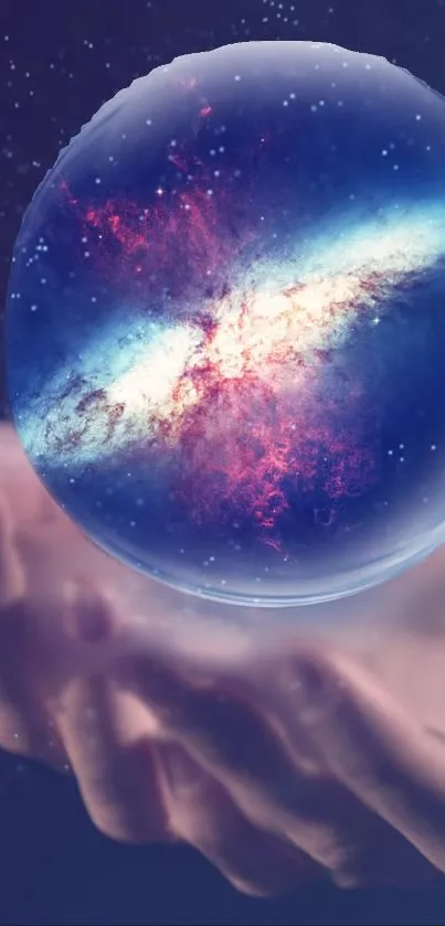 A galaxy encased in a crystal ball, held in a hand, against a dark blue cosmic background.