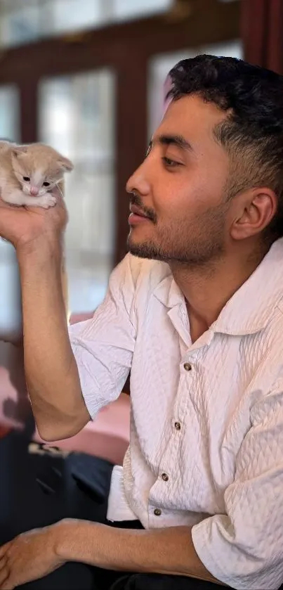 Man holding a kitten with a warm and gentle expression.