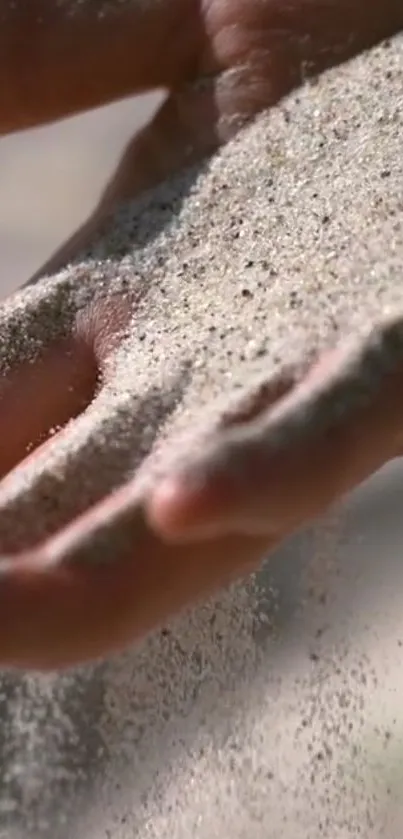 Close-up of sand gently falling through fingers on a hand.