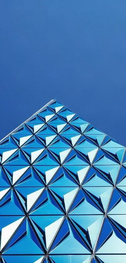 Geometric reflections on a blue glass pyramid under a clear sky.