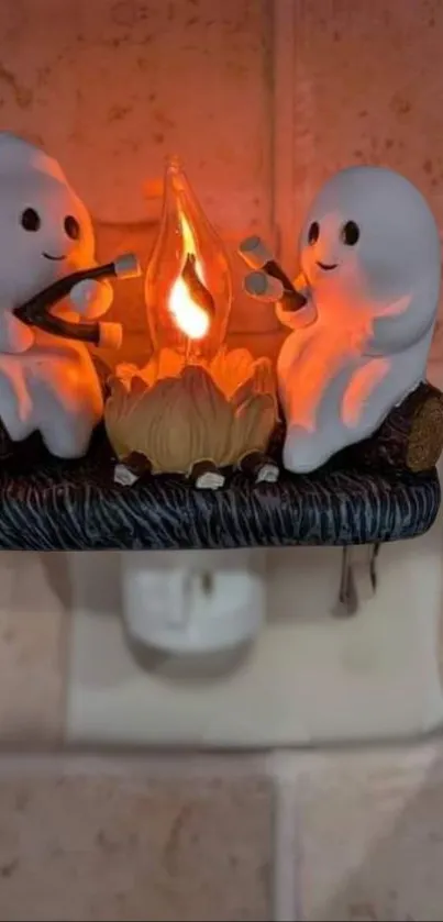 Two ceramic ghosts with a campfire nightlight glow.