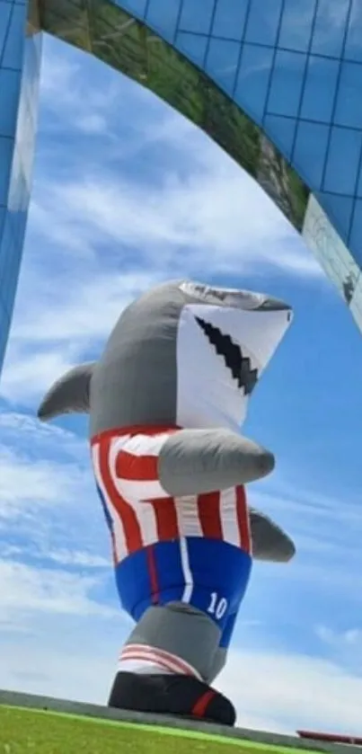 Inflatable shark in front of mirrored building under blue sky.